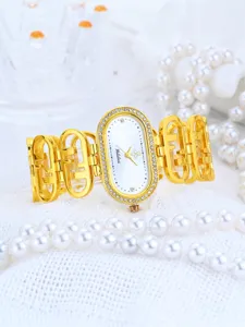 Luxury gold oval watch close-up, rhinestone bezel, elegant hollow metal strap detail.