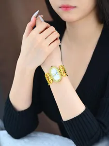 Close-up detail of luxury gold quartz watch with diamond-set oval dial and link bracelet.