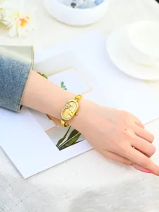 Elegante reloj de mujer dorado ovalado con esfera pequeña, bisel de cristal y correa de acero fina.