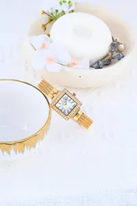Detail shot of women luxury square rhinestone quartz watch with gold mesh strap dial closeup.