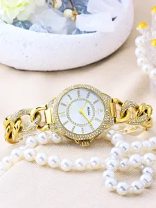 Vista detallada del reloj de cuarzo con estras dorado, correa de cadena y esfera blanca elegante.
