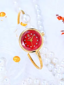 Dettaglio orologio bracciale oro quadrante sfaccettato rosso con strass e perle fini.