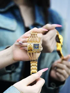 Primer plano de reloj de pulsera dorado para mujer con correa de jaula y esfera de diamantes.