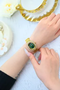 Exquisito reloj de cuarzo ovalado para mujer con esfera verde y correa de metal dorado.