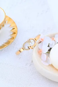 Elegante reloj de pulsera dorado para mujer con correa fina y esfera con pedrería.
