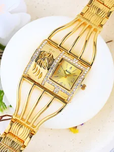 Primer plano del reloj de pulsera dorado para mujer con correa de jaula y pedrería brillante.