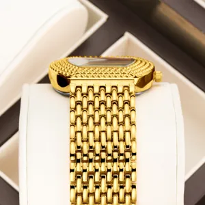 Golden tonneau quartz watch with textured link bracelet and paved bezel for women.