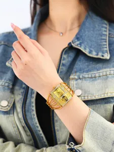 Primer plano detallado de un reloj de pulsera dorado para mujer con esfera cuadrada.