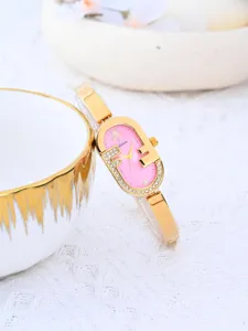 Vista detallada de reloj de mujer dorado con esfera rosa y pedrería, diseño elegante vintage.