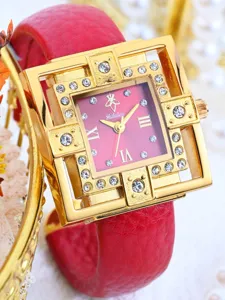 Detailed close-up of a luxury square-dial rhinestone watch with red leather bracelet strap.