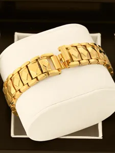 Golden metal watch strap detail showing exquisite geometric carved links and polished finish.