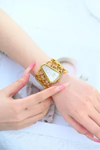 Gedetailleerde close-up van het elegante gouden quartz horloge met driehoekige wijzerplaat.