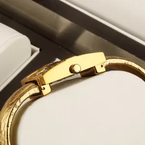 Luxury gold bangle quartz watch for women, elegant curved case side view for daily wear.