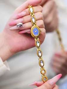 Gold tone chain watch close up featuring a blue oval dial and sparkling crystal links.