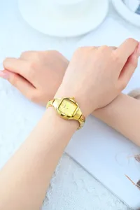 Close-up detail shot of luxury gold wristwatch with tonneau dial and crystal markers on wrist.