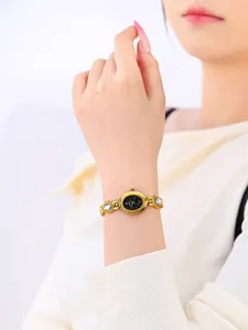 Close-up detail of women's vintage gold chain watch with black dial and crystal links.
