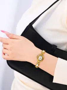 Close-up view of a vintage gold-toned oval quartz watch with crystal link bracelet details.