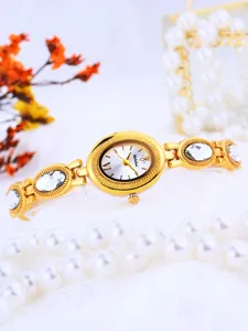 Gold dial detail of women quartz watch with crystal rhinestone links and pearl background.