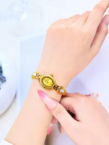 Close-up detail shot of the golden vintage oval quartz watch with crystal accent bracelet.