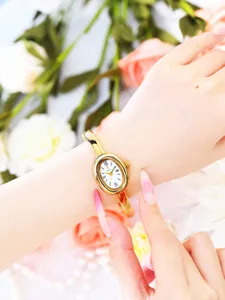 Detailed shot of the yalalusi gold oval bangle quartz watch worn gracefully on the wrist.