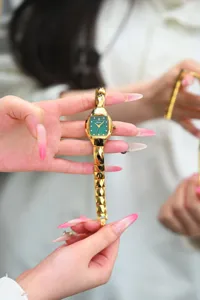 Elegant vintage tonneau-shaped women's watch with green dial and metallic gold geometric strap.