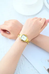 Women gold tonneau quartz watch detail, elegant retro small dial timepiece with metal strap.