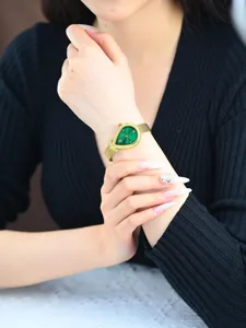 Detailaufnahme der tropfenförmigen grünen Quarz-Damenuhr mit goldenem Mesh-Armband und Steinen.
