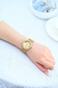 Elegant women's rhinestone quartz watch with gold mesh strap, vintage luxury detail close-up.