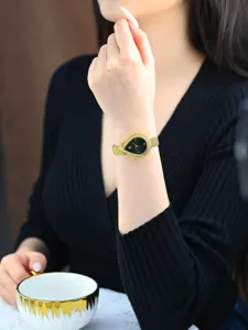 Elegante tropfenförmige Damen Quarzarmbanduhr mit schwarzem Zifferblatt und goldenem Armband.