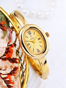 Golden oval quartz bangle watch detail view with Roman numerals and elegant vintage design.