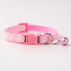 Close-up of pink pet collar detail, featuring cute paw print patterns and metal bell.