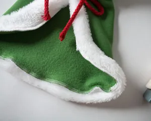 Close-up detail of Christmas green pet cape with plush white trim and red drawstring.