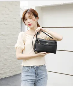 Detailed view of a black PU leather crossbody shoulder bag worn by a model in an outdoor setting.