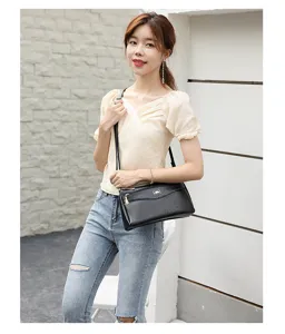 Detail shot of a stylish black PU leather crossbody bag worn by an Asian model in daily scene.