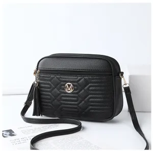 Vue détaillée du sac à bandoulière matelassé noir avec logo en métal et pompon élégant.