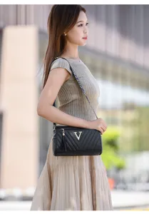 Detailed shot of a black quilted shoulder bag with gold V logo and chic tassel pendant.