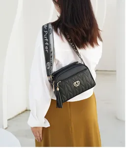 Detail shot of a stylish black quilted shoulder bag with tassel and logo strap.