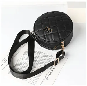 Detailed view of black quilted round crossbody bag with adjustable strap and chic metal plate.