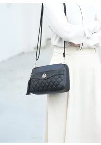Detailed view of the black quilted crossbody bag featuring elegant tassel charm and gold M logo.