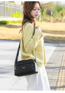 Detailed view of women black quilted shoulder bag with woven strap and metal logo accent.