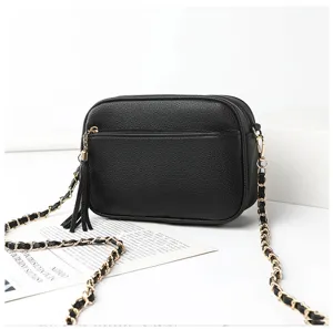 Detailed view of stylish black crossbody camera bag with gold chain strap and tassel charm.