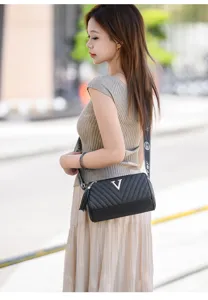Women black quilted cylinder crossbody shoulder bag with metal V logo and wide strap.