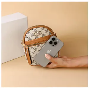 Detail view of a compact vertical monogram crossbody phone bag with brown leather trim.