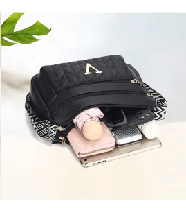 Black quilted leather shoulder bag interior detail showing large capacity, multi-zipper pockets and wide strap.