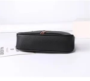 Detail view of black soft leather crossbody bag featuring classic striped web strap and texture.