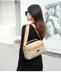 Shoulder bag detail view showing monogram pattern, wide strap and metal logo accent.