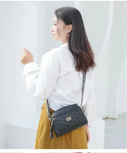 Detail shot of black quilted crossbody shoulder bag with stylish geometric pattern and strap.
