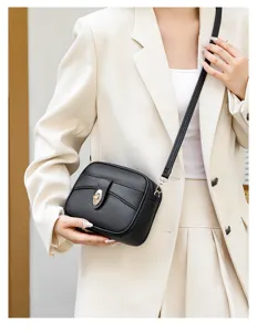 Detailed view of black minimalist crossbody bag with gold turn-lock closure and slim strap.