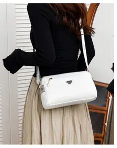 Vue détaillée du sac à bandoulière blanc pour femme avec texture et logo en métal.