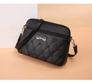 Black quilted crossbody bag with cute bow and heart embroidery details, close-up shot.